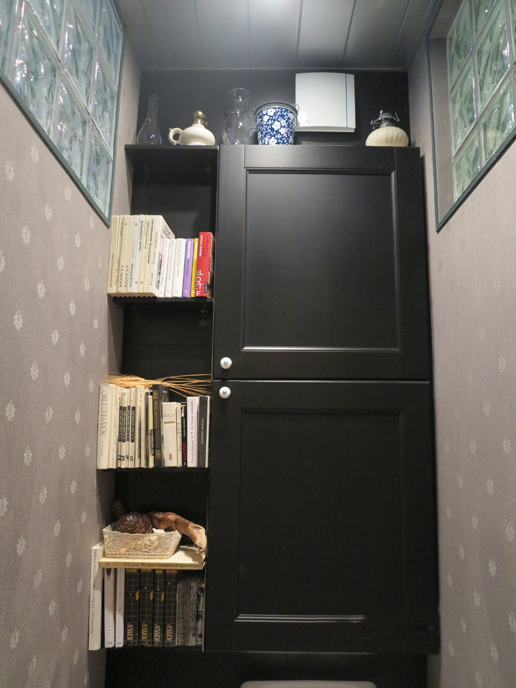 This is an example of a small traditional powder room in Moscow with raised-panel cabinets, black cabinets, a one-piece toilet, black walls, porcelain floors and black floor.