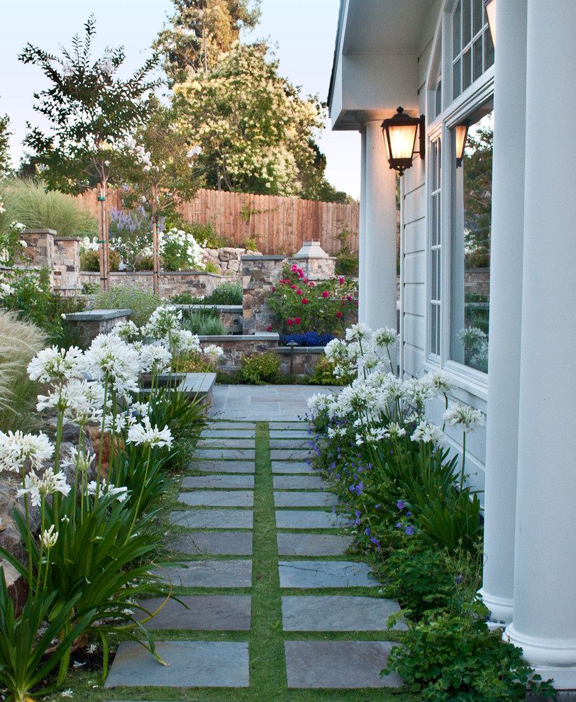 This is an example of a traditional side yard partial sun garden for spring in San Francisco with natural stone pavers and with path.