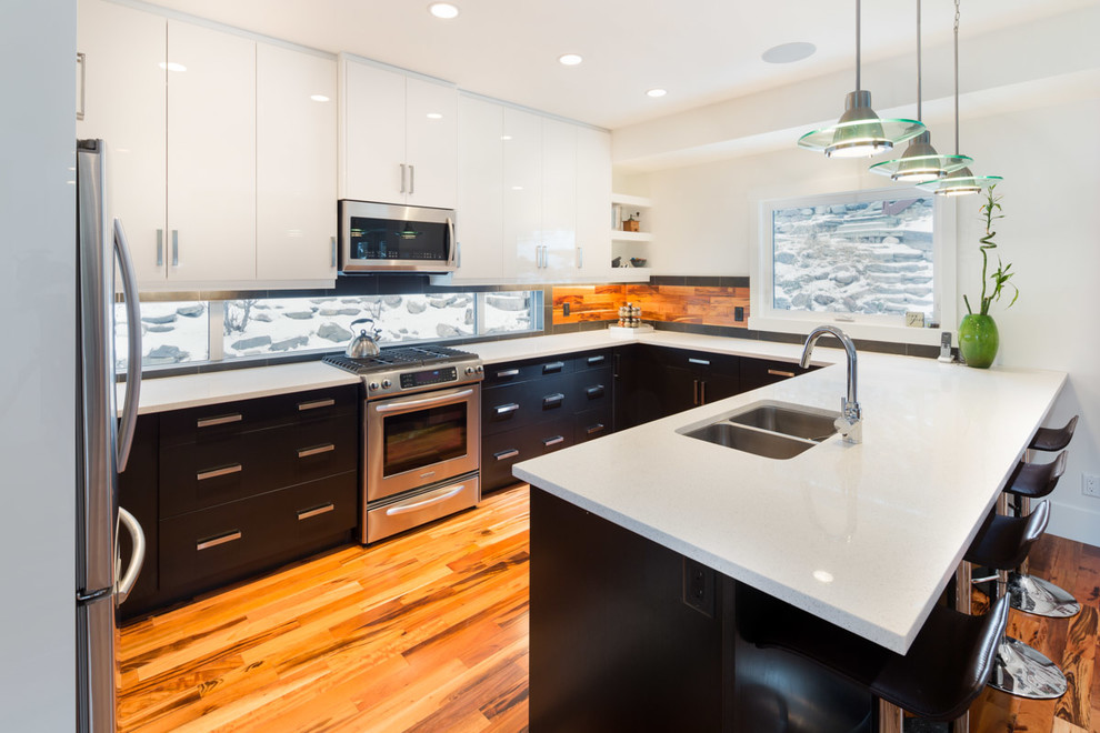 Photo of a mid-sized modern u-shaped eat-in kitchen in Other with an undermount sink, flat-panel cabinets, quartz benchtops, stainless steel appliances, a peninsula and brown floor.