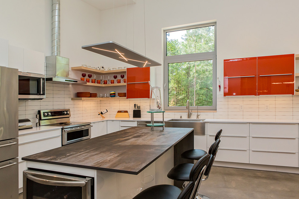 Design ideas for a mid-sized modern l-shaped open plan kitchen in Raleigh with a farmhouse sink, flat-panel cabinets, orange cabinets, quartz benchtops, white splashback, ceramic splashback, stainless steel appliances, concrete floors, with island, grey floor and multi-coloured benchtop.