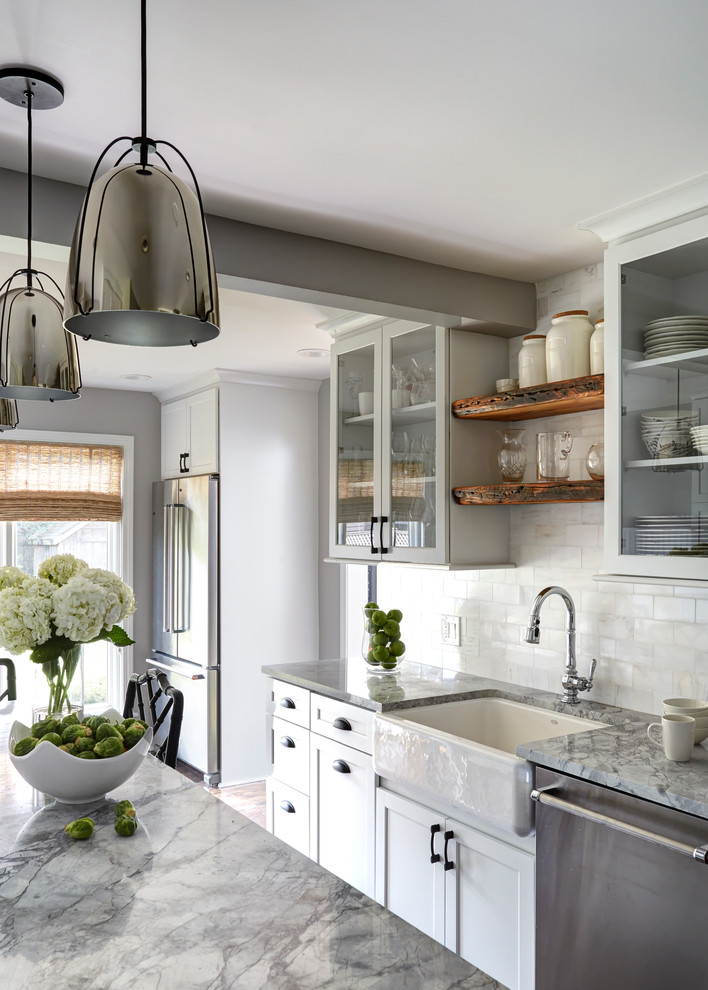 Kitchen - transitional medium tone wood floor kitchen idea in Chicago with a farmhouse sink, white cabinets, quartzite countertops, white backsplash, stone tile backsplash, stainless steel appliances and an island