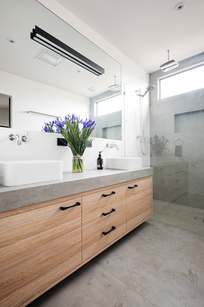 Mid-sized modern master bathroom in Melbourne with flat-panel cabinets, light wood cabinets, a freestanding tub, a double shower, a two-piece toilet, white tile, porcelain tile, white walls, porcelain floors, a vessel sink, grey floor and an open shower.