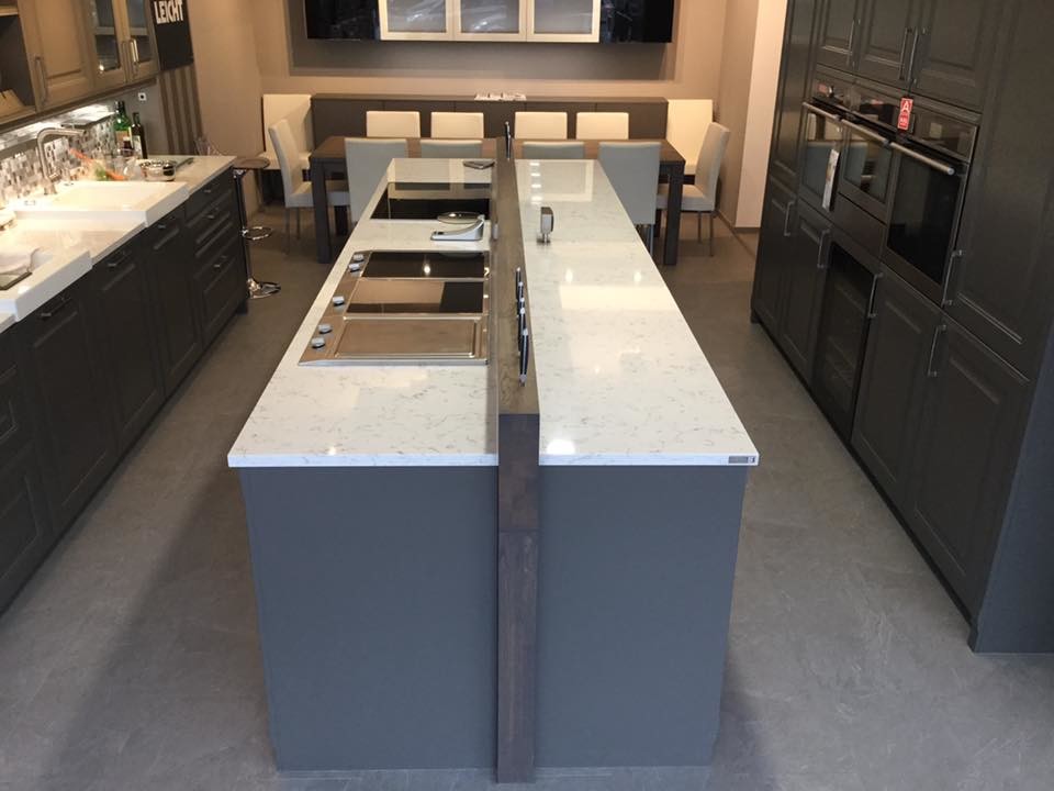 Large contemporary galley eat-in kitchen in Houston with a farmhouse sink, raised-panel cabinets, grey cabinets, quartz benchtops, multi-coloured splashback, glass tile splashback, black appliances, slate floors and with island.