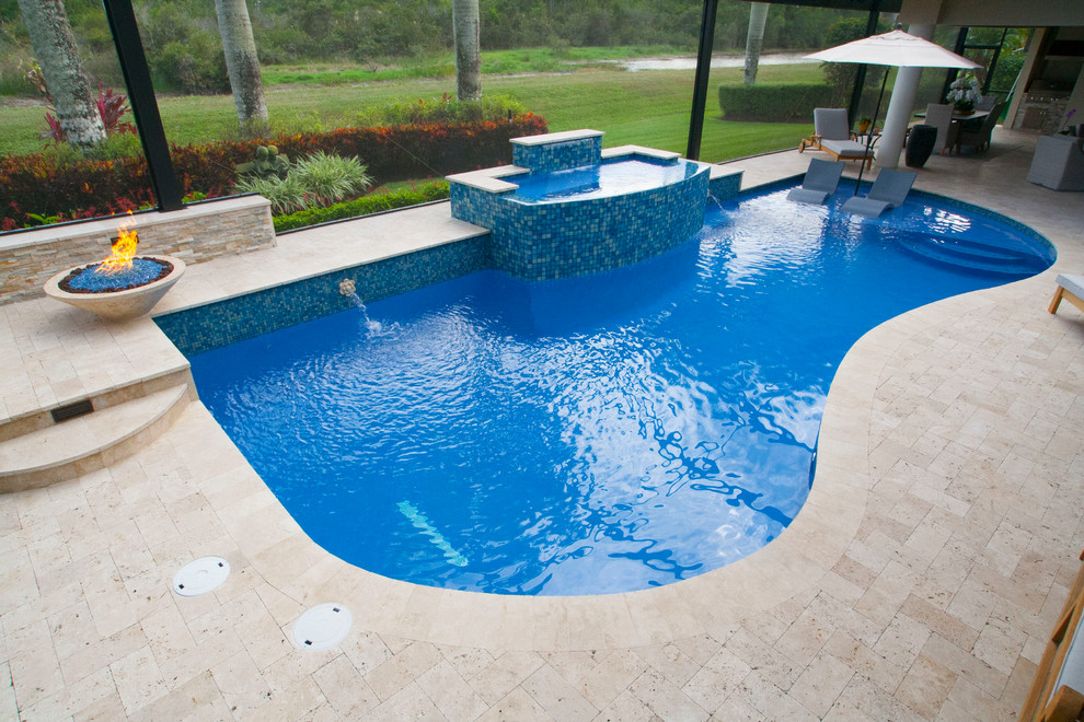 Large modern backyard custom-shaped pool in Miami with a water feature and natural stone pavers.