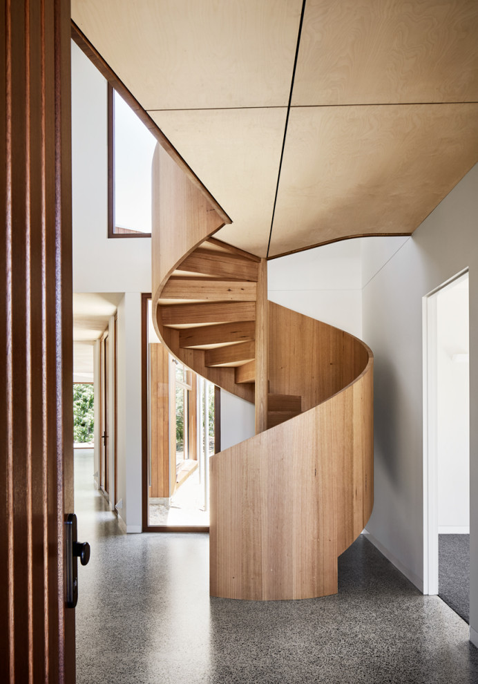 Idée de décoration pour un grand escalier hélicoïdal design avec des marches en bois, des contremarches en bois et un garde-corps en bois.