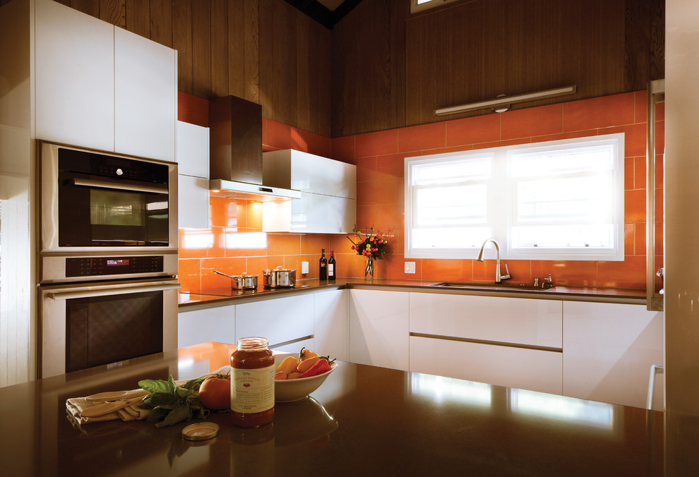 This is an example of a mid-sized modern u-shaped separate kitchen in Hawaii with an undermount sink, flat-panel cabinets, white cabinets, quartz benchtops, orange splashback, ceramic splashback, stainless steel appliances, ceramic floors and a peninsula.