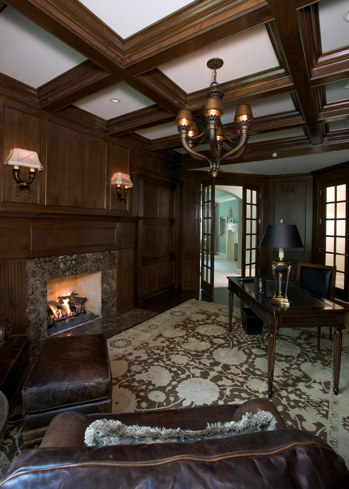 Expansive traditional home office in Chicago with a library, brown walls, dark hardwood floors, a standard fireplace, a stone fireplace surround and a freestanding desk.