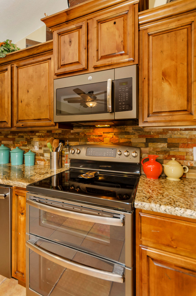 Mid-sized mountain style u-shaped porcelain tile home design photo in Phoenix with a farmhouse sink, raised-panel cabinets, medium tone wood cabinets, granite countertops, orange backsplash, stone tile backsplash, stainless steel appliances and no island