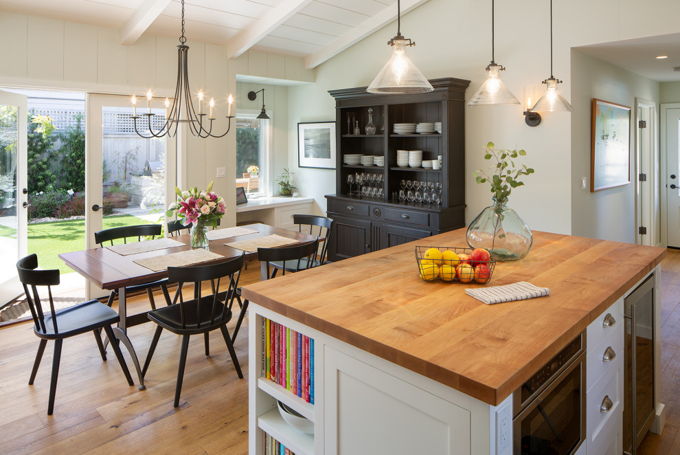 Example of a mid-sized beach style l-shaped medium tone wood floor, brown floor and shiplap ceiling eat-in kitchen design in San Diego with shaker cabinets, white cabinets, wood countertops, stainless steel appliances, an island and brown countertops