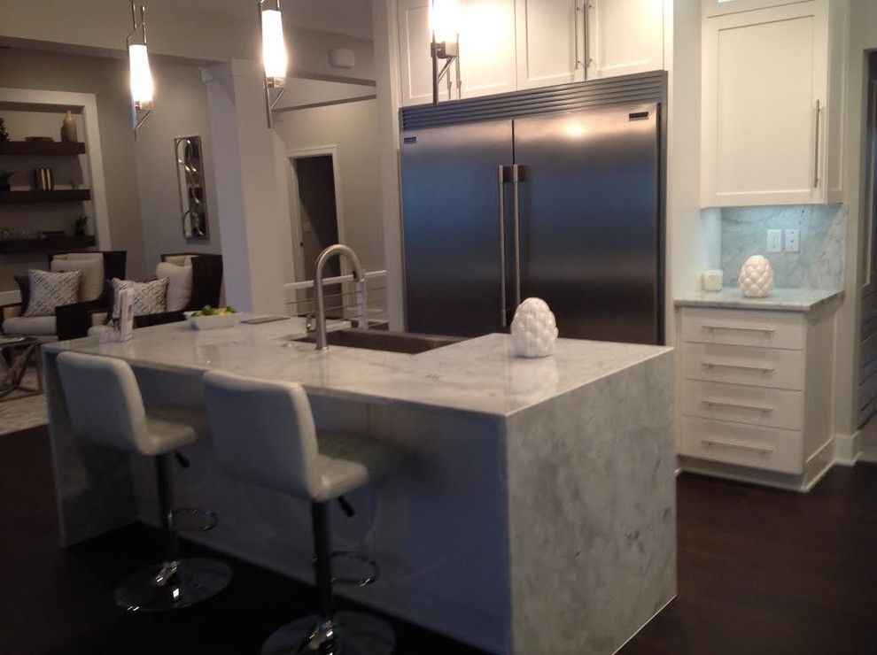 Inspiration for a mid-sized transitional single-wall dark wood floor and brown floor open concept kitchen remodel with a farmhouse sink, shaker cabinets, white cabinets, marble countertops, white backsplash, stone slab backsplash, stainless steel appliances and an island