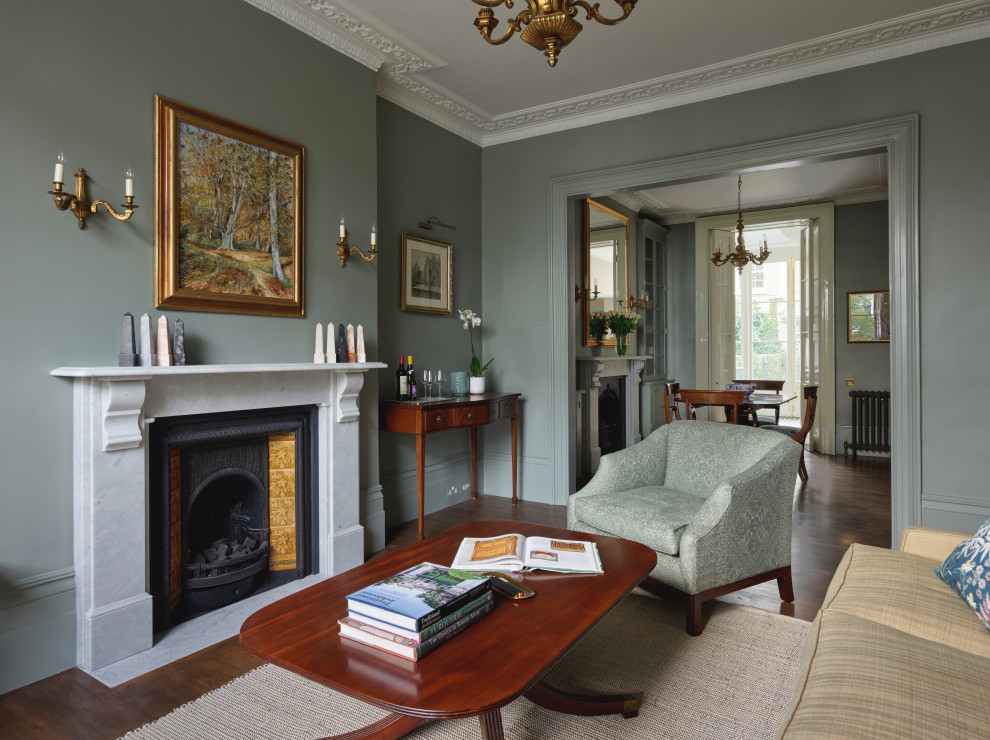 This is an example of a large victorian grey and brown open plan living room in London with green walls, dark hardwood flooring, a standard fireplace, a stone fireplace surround, no tv, brown floors and a chimney breast.