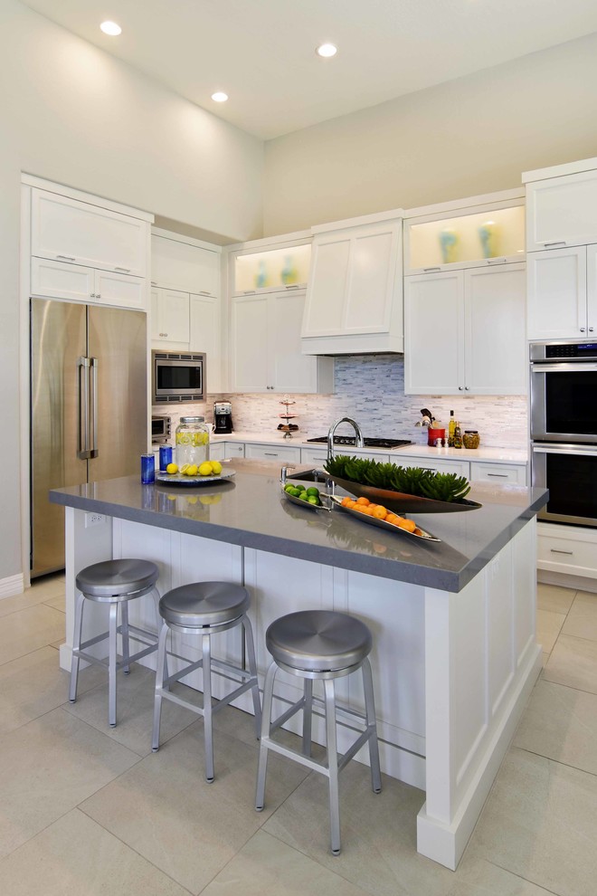 Photo of a large transitional u-shaped eat-in kitchen in Phoenix with an undermount sink, recessed-panel cabinets, white cabinets, quartz benchtops, white splashback, stone tile splashback, stainless steel appliances, porcelain floors, with island, beige floor and grey benchtop.
