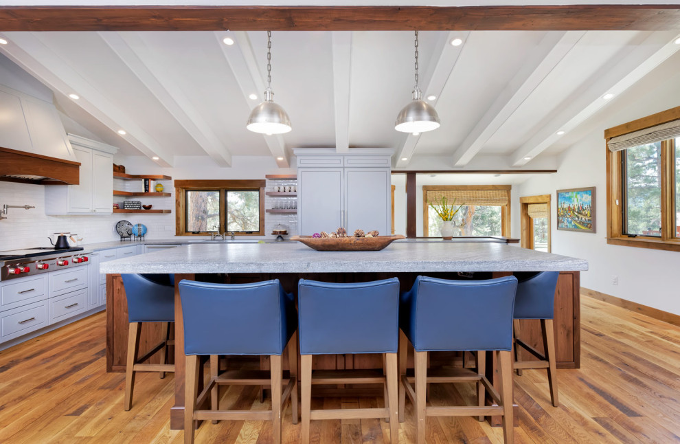 Mid-sized mountain style l-shaped medium tone wood floor open concept kitchen photo with an undermount sink, shaker cabinets, granite countertops, beige backsplash, stainless steel appliances and an island