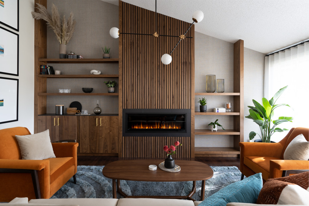 Photo of a small midcentury enclosed living room in Calgary with a standard fireplace, a wood fireplace surround, wallpaper, white walls, dark hardwood floors, no tv and brown floor.