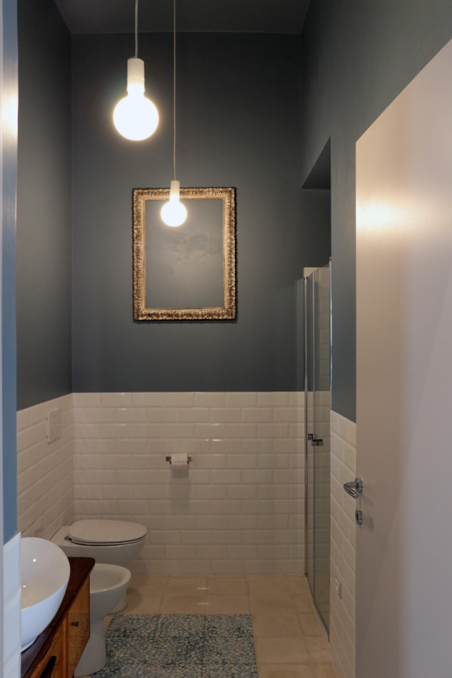 This is an example of a mid-sized eclectic 3/4 bathroom in Other with medium wood cabinets, an alcove shower, a two-piece toilet, white tile, subway tile, blue walls, cement tiles, a vessel sink, glass benchtops, multi-coloured floor, a hinged shower door and a single vanity.