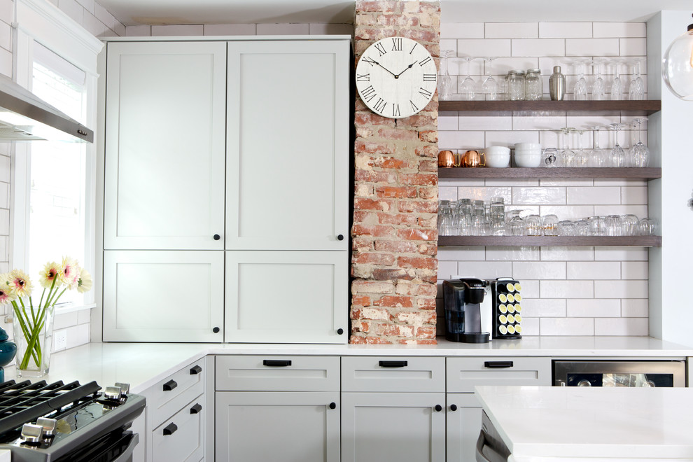 Eat-in kitchen - mid-sized transitional galley brown floor eat-in kitchen idea in Atlanta with a drop-in sink, glass-front cabinets, white cabinets, quartzite countertops, white backsplash, subway tile backsplash, stainless steel appliances and an island
