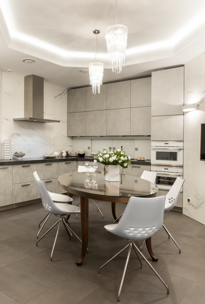 This is an example of a mid-sized contemporary l-shaped eat-in kitchen in Moscow with flat-panel cabinets, grey cabinets, white splashback, white appliances, porcelain floors, no island, a drop-in sink, tile benchtops, porcelain splashback and brown floor.