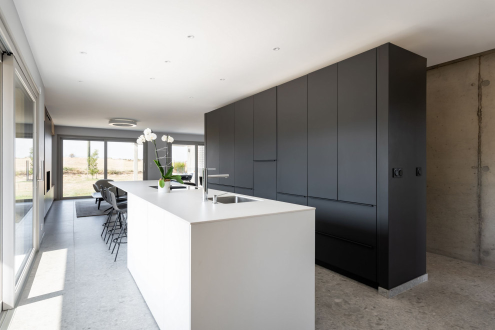 This is an example of a large modern open plan kitchen in Saint-Etienne with a submerged sink, black cabinets, quartz worktops, an island and white worktops.