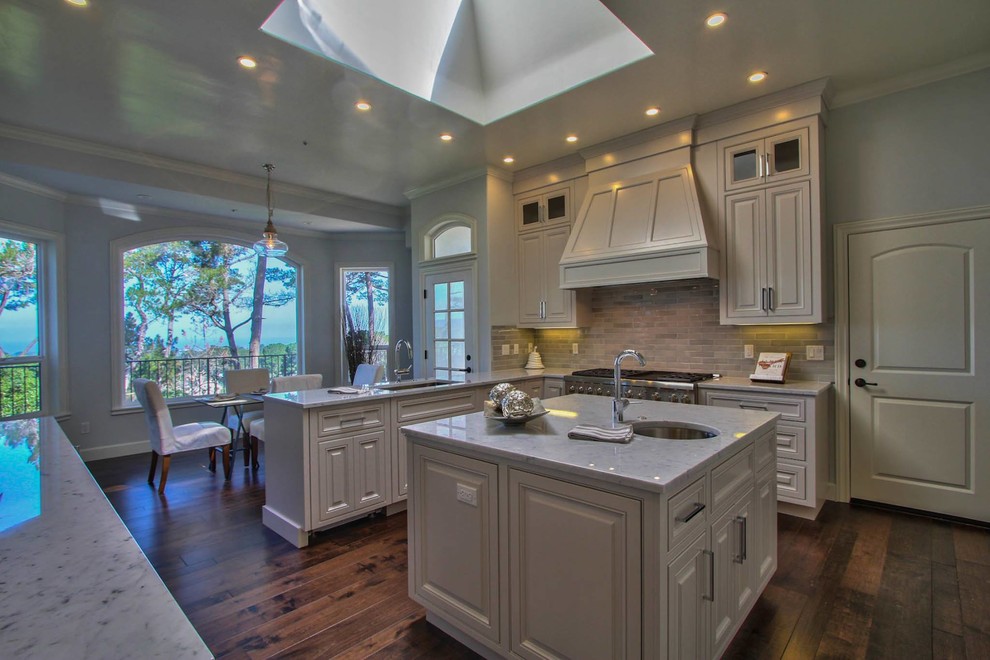 Kitchen - transitional dark wood floor kitchen idea with an undermount sink, raised-panel cabinets, white cabinets, marble countertops, beige backsplash and stainless steel appliances