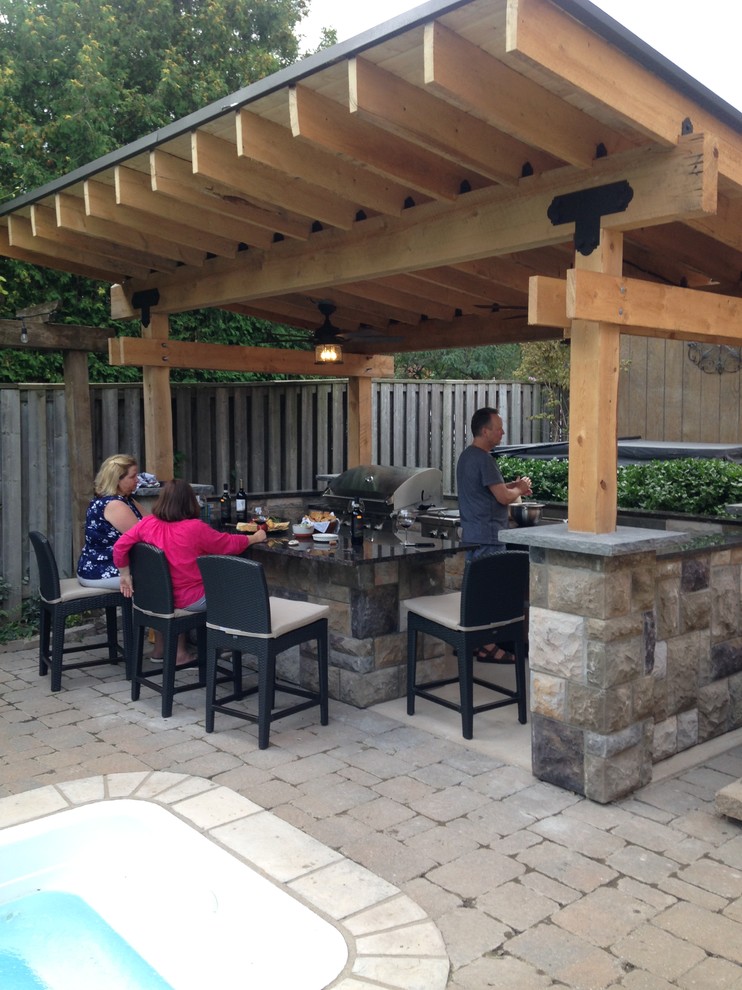 Mid-sized arts and crafts backyard patio in Toronto with an outdoor kitchen, concrete slab and a gazebo/cabana.
