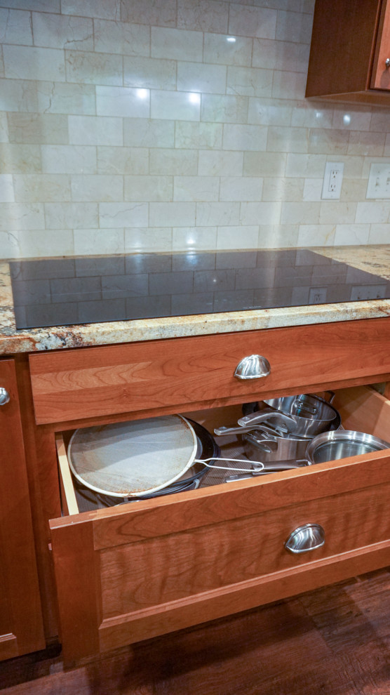 Mid-sized u-shaped laminate floor enclosed kitchen photo with a double-bowl sink, recessed-panel cabinets, medium tone wood cabinets, granite countertops, beige backsplash, ceramic backsplash, stainless steel appliances and an island