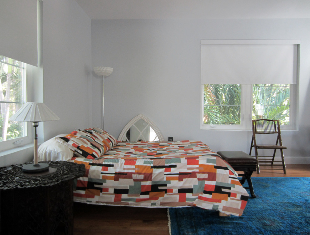 This is an example of a large eclectic guest bedroom in Miami with grey walls and medium hardwood floors.