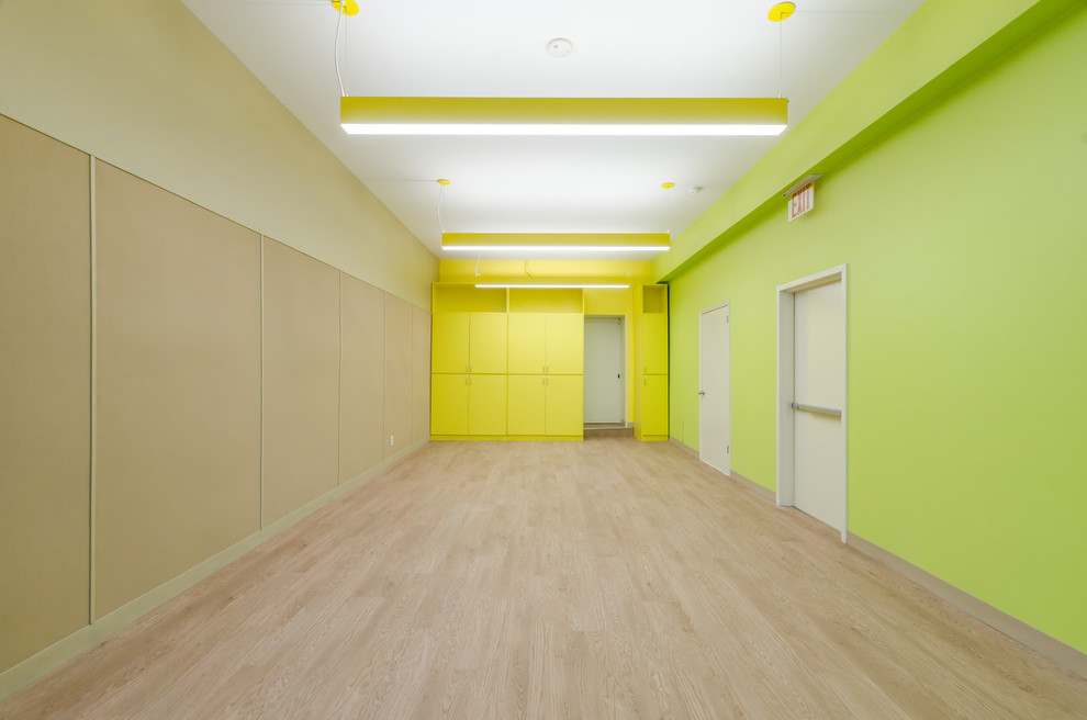 Photo of a small contemporary gender-neutral kids' room in New York with yellow walls, laminate floors and beige floor.