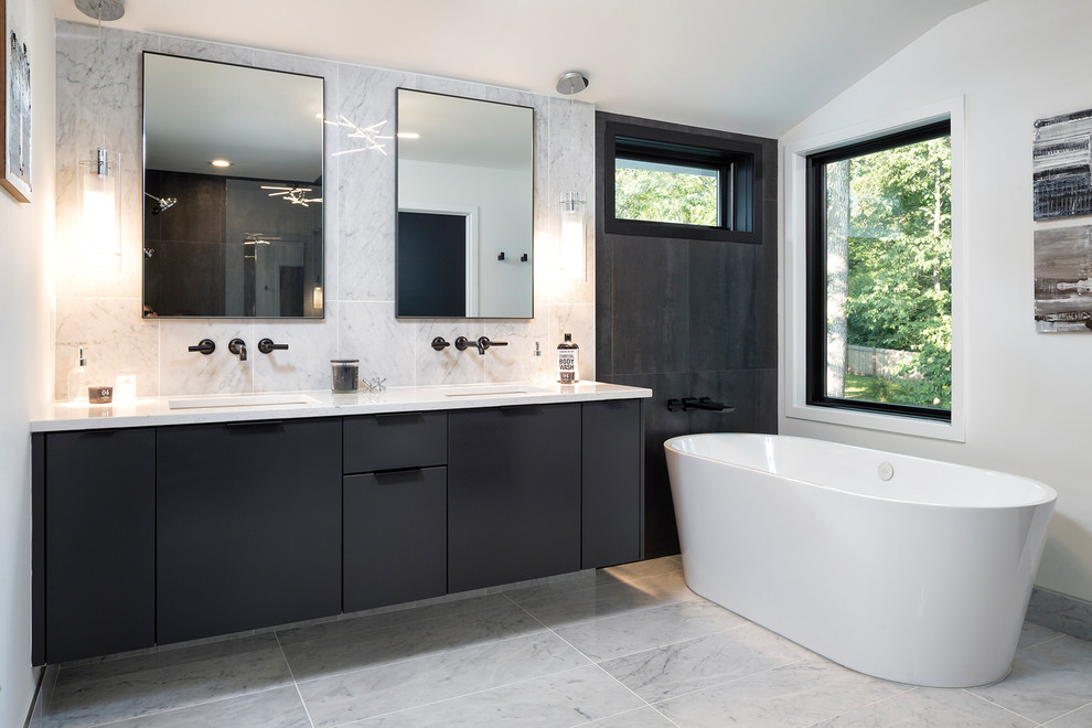 Photo of a mid-sized contemporary bathroom in Minneapolis with flat-panel cabinets, black cabinets, a freestanding tub, white walls, an undermount sink, white floor, white benchtops, marble floors and engineered quartz benchtops.