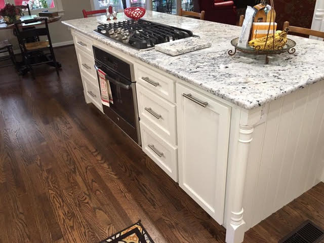 Inspiration for a mid-sized transitional l-shaped dark wood floor and brown floor eat-in kitchen remodel in Birmingham with an undermount sink, recessed-panel cabinets, white cabinets, white backsplash, stainless steel appliances and an island