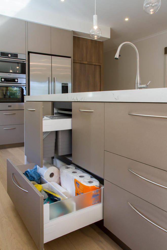This is an example of a large contemporary l-shaped open plan kitchen in Melbourne with flat-panel cabinets, quartz benchtops and with island.