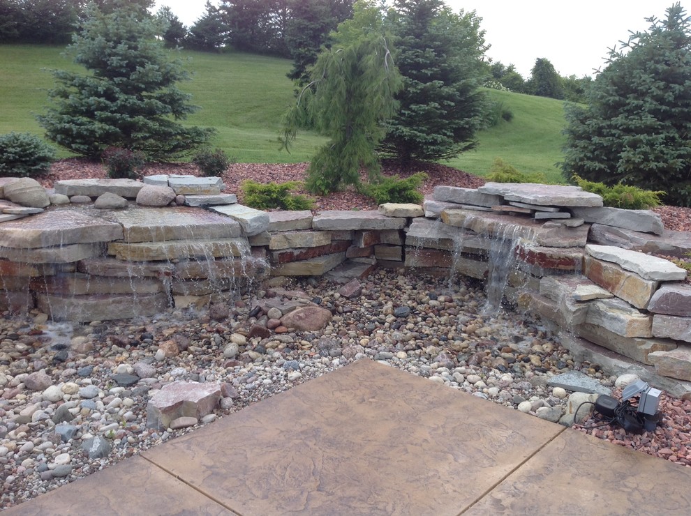 Inspiration for a large backyard rectangular natural pool in Milwaukee with a water feature and stamped concrete.