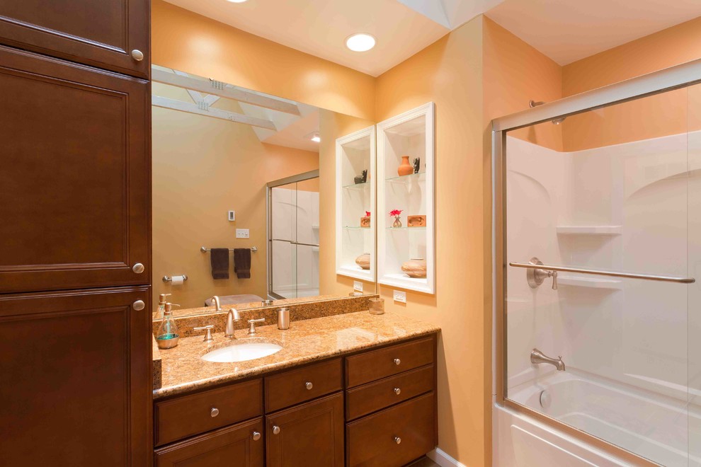 Mid-sized traditional bathroom in Other with medium wood cabinets, an undermount sink, granite benchtops, orange walls, recessed-panel cabinets and brown benchtops.