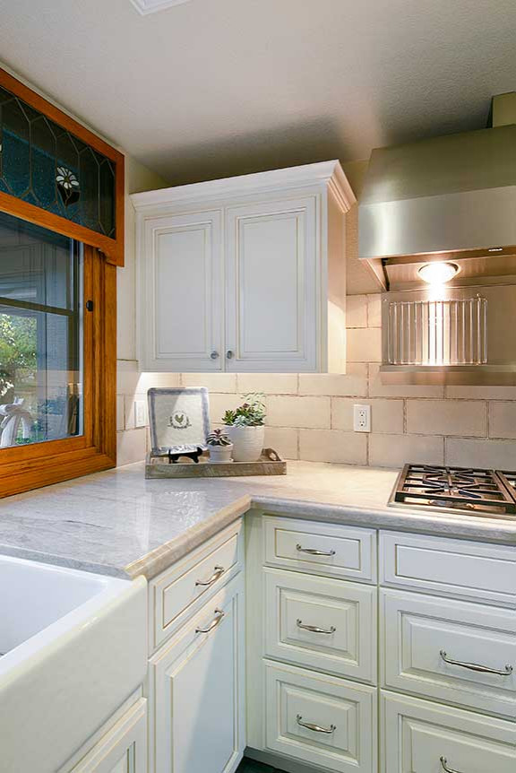 Eat-in kitchen - large traditional u-shaped ceramic tile and blue floor eat-in kitchen idea in San Francisco with a farmhouse sink, raised-panel cabinets, white cabinets, quartzite countertops, white backsplash, ceramic backsplash, stainless steel appliances, an island and white countertops
