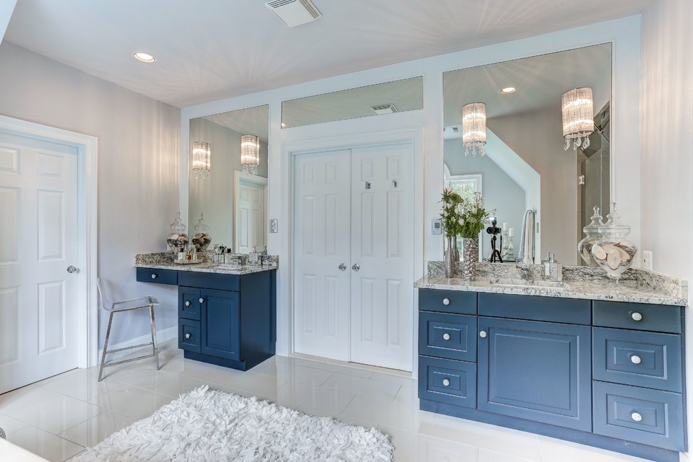 Photo of a large contemporary master bathroom in DC Metro with raised-panel cabinets, blue cabinets, a freestanding tub, grey walls, an undermount sink, a hinged shower door and multi-coloured benchtops.