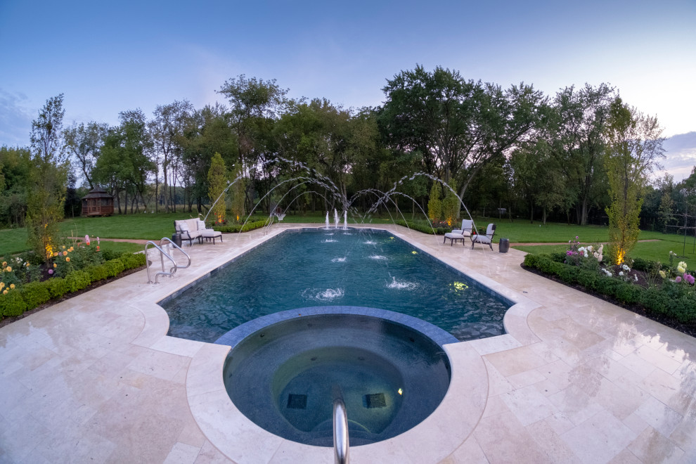 Photo of a mid-sized mediterranean backyard custom-shaped lap pool in Chicago with a hot tub and natural stone pavers.