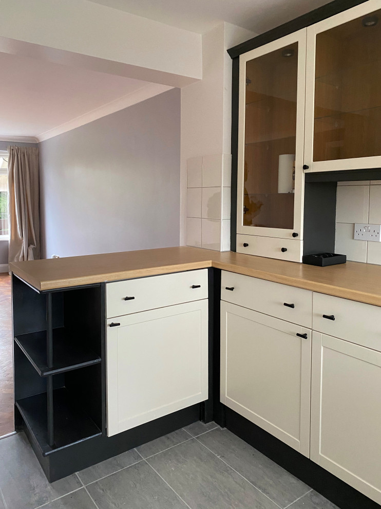 Design ideas for a small contemporary l-shaped open plan kitchen in London with a submerged sink, shaker cabinets, beige cabinets, laminate countertops, beige splashback, ceramic splashback, stainless steel appliances, porcelain flooring, a breakfast bar, pink floors and brown worktops.
