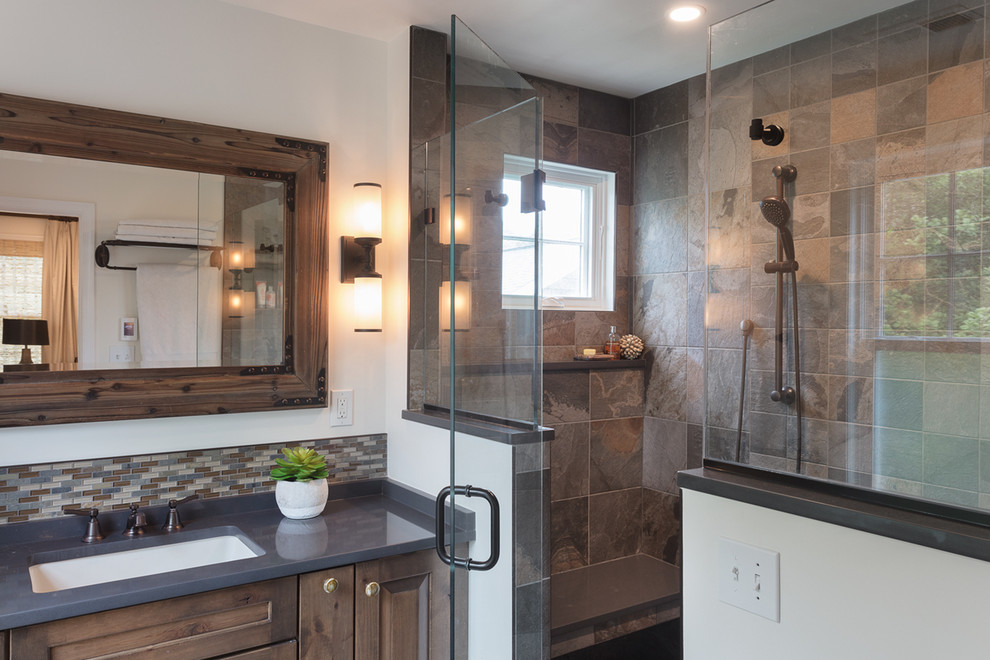 Photo of a mid-sized country master bathroom in DC Metro with raised-panel cabinets, brown cabinets, an alcove shower, brown tile, slate, white walls, an undermount sink, engineered quartz benchtops, a hinged shower door and grey benchtops.