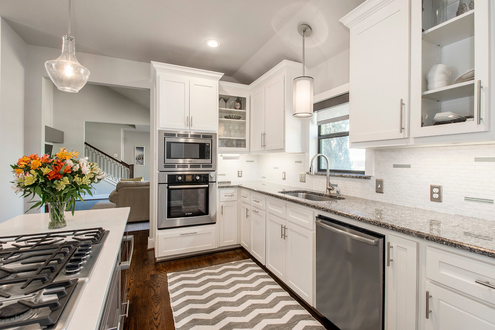 Transitional l-shaped eat-in kitchen in Dallas with an undermount sink, shaker cabinets, white splashback, stainless steel appliances, medium hardwood floors and with island.