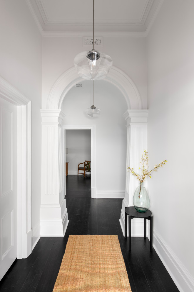 Immagine di un ingresso vittoriano di medie dimensioni con pareti bianche, pavimento in legno verniciato, una porta singola, una porta nera, pavimento nero e pareti in mattoni