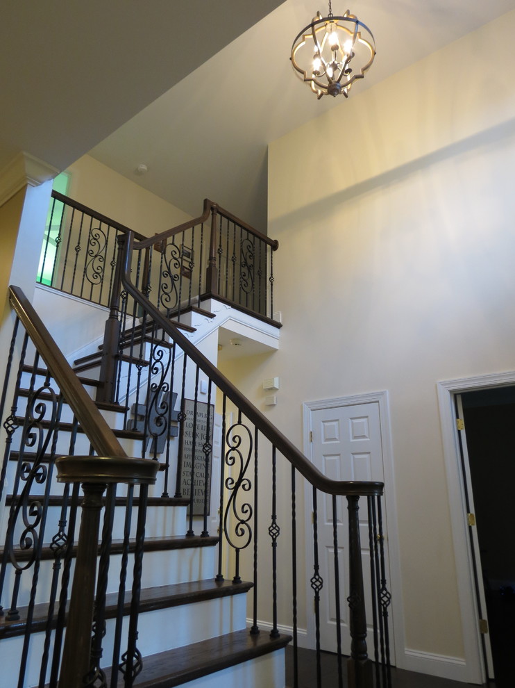 Example of a large transitional galley dark wood floor and brown floor staircase design with a double-bowl sink, raised-panel cabinets, white cabinets, granite countertops, white backsplash, porcelain backsplash, stainless steel appliances and an island
