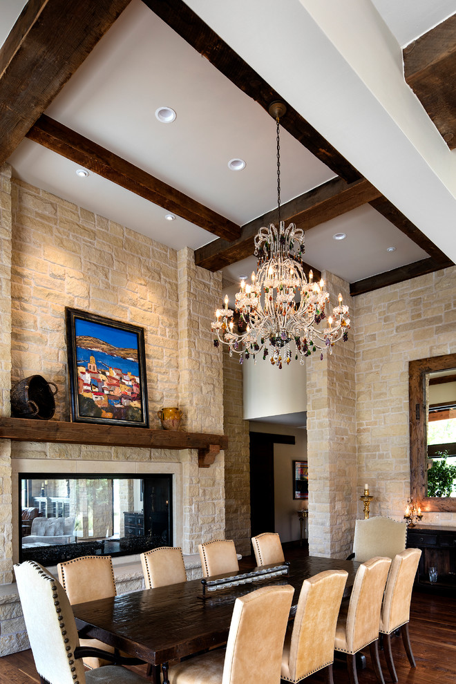 Large country open plan dining in Wichita with beige walls, dark hardwood floors, a two-sided fireplace and a stone fireplace surround.