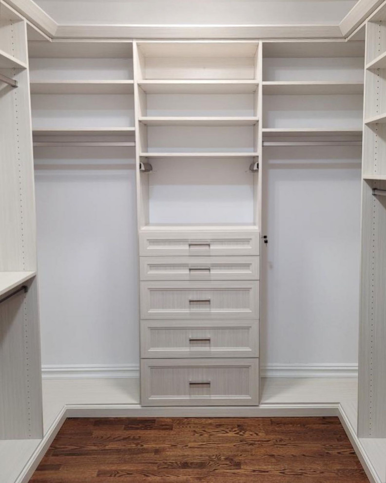 Design ideas for a mid-sized traditional gender-neutral walk-in wardrobe in New York with recessed-panel cabinets, beige cabinets, dark hardwood floors and brown floor.