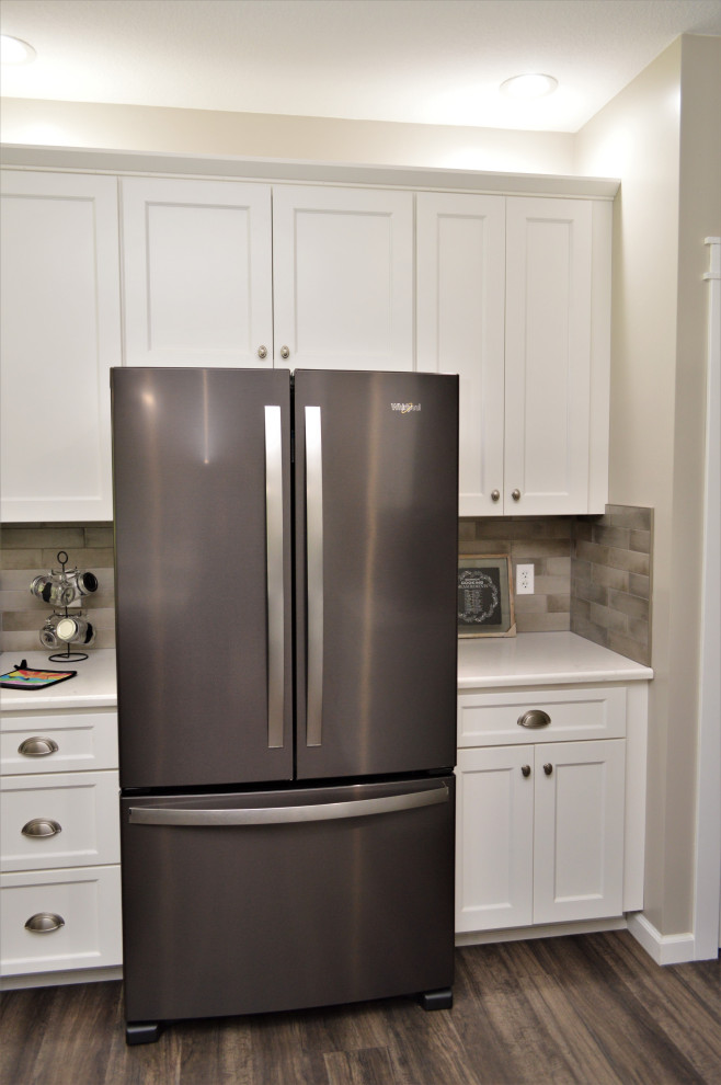 Inspiration for a mid-sized transitional single-wall open concept kitchen remodel with a drop-in sink, shaker cabinets, white cabinets, quartzite countertops, beige backsplash, stainless steel appliances, an island and white countertops