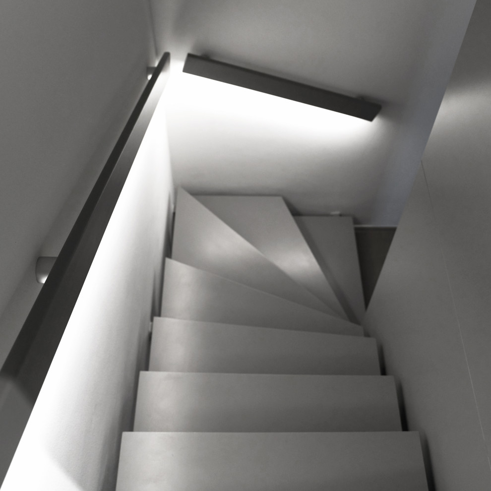 Graue Treppe mit schwarzem Handlauf mit integrierter, indirekter Beleuchtung