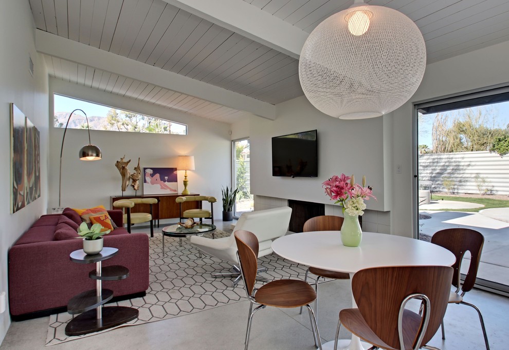 Photo of a mid-sized midcentury open concept family room in Los Angeles with white walls, concrete floors, a standard fireplace, a tile fireplace surround and a wall-mounted tv.
