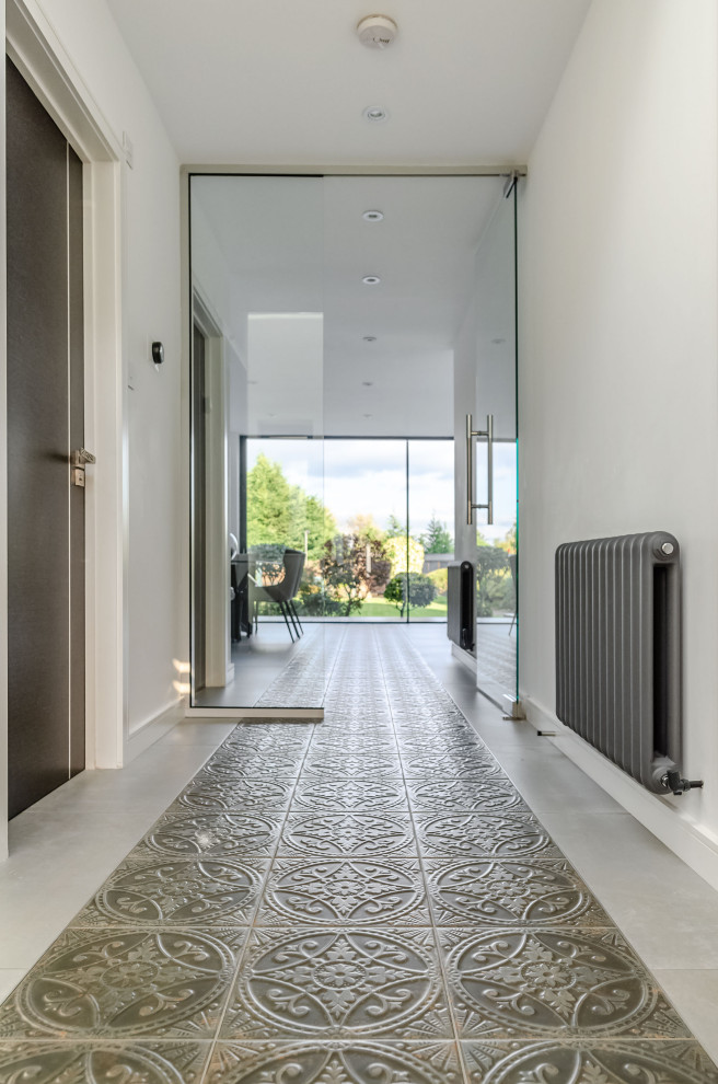 This is an example of a large contemporary hallway in Essex with white walls, porcelain flooring and grey floors.