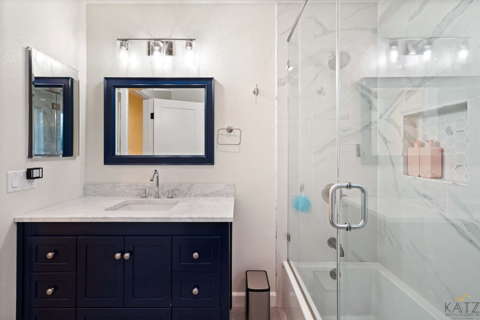 Пример оригинального дизайна: ванная комната с синими фасадами, унитазом-моноблоком, белой плиткой, мраморной плиткой, бежевыми стенами, паркетным полом среднего тона, консольной раковиной, мраморной столешницей, оранжевым полом, белой столешницей, тумбой под одну раковину и встроенной тумбой