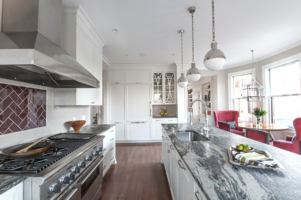 Photo of a mid-sized transitional l-shaped eat-in kitchen in Boston with an undermount sink, recessed-panel cabinets, white cabinets, dark hardwood floors, with island, white splashback, subway tile splashback, brown floor, panelled appliances and grey benchtop.