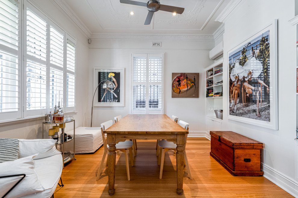 Photo of an eclectic dining room in Sydney with white walls, medium hardwood floors and brown floor.