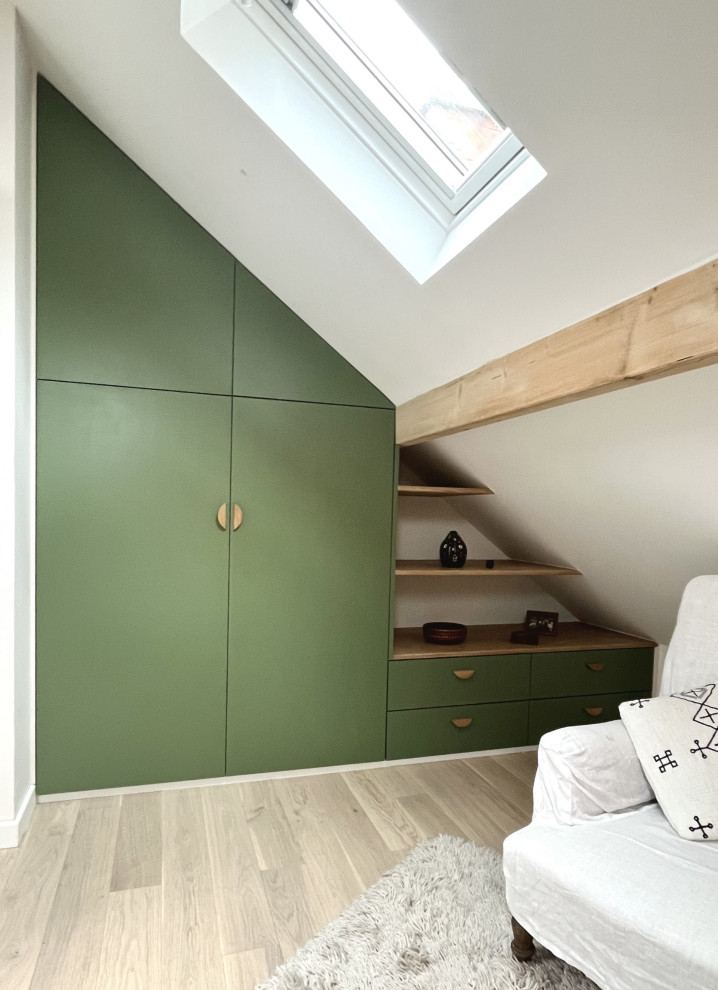 Inspiration for a medium sized contemporary standard wardrobe in Paris with beaded cabinets, green cabinets, light hardwood flooring, beige floors and exposed beams.